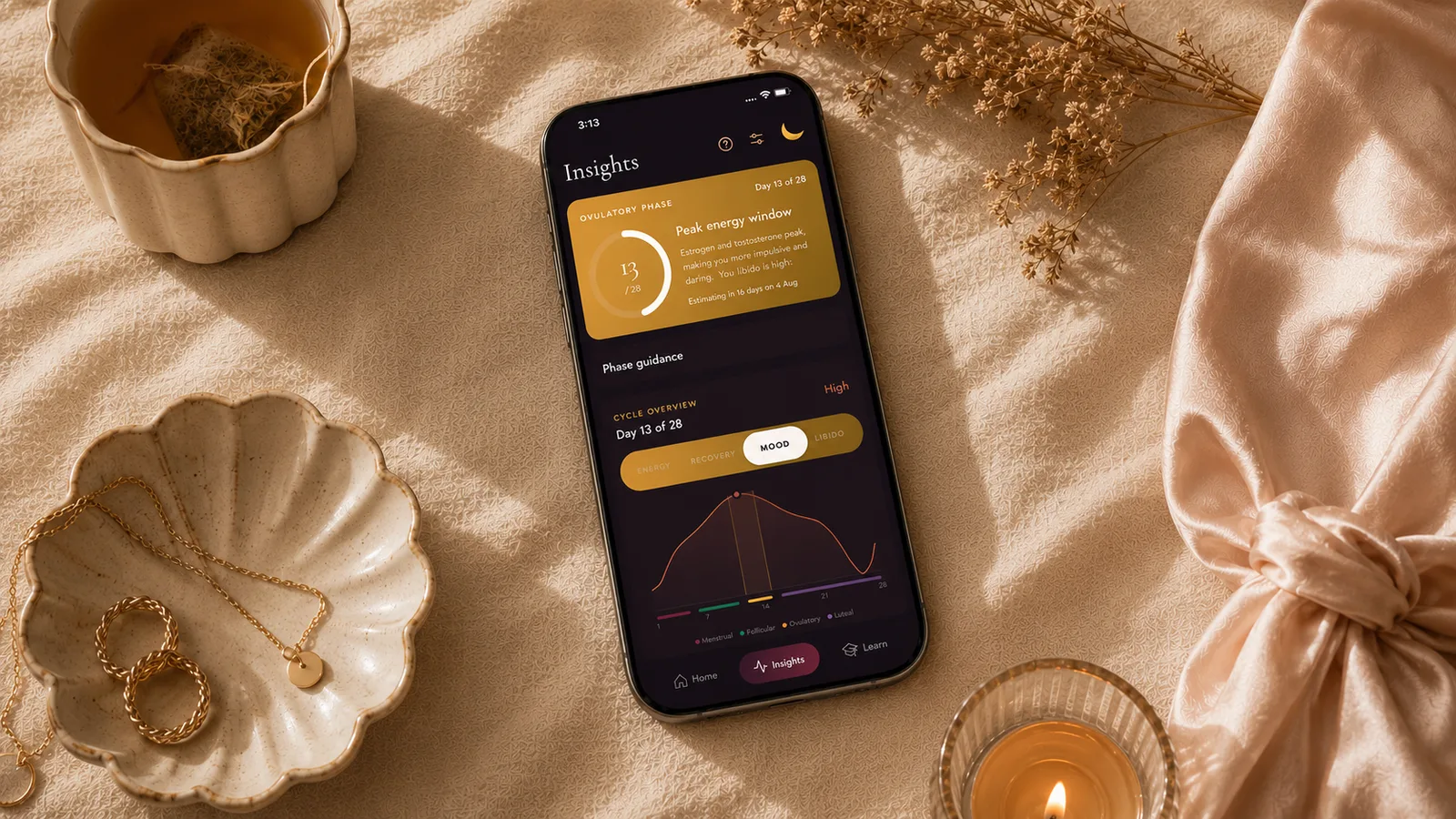 The Luna app resting among tea, dried flowers and candlelight