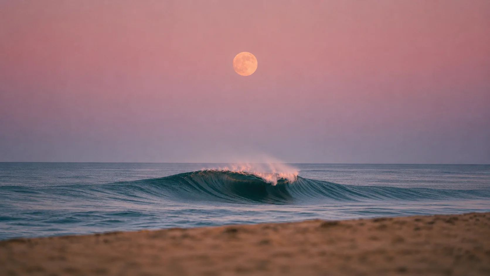 A full moon rising over a breaking wave at dusk